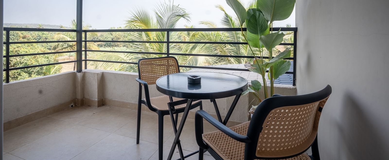 Private balcony with a table and chairs overlooking lush greenery at Kssemya.