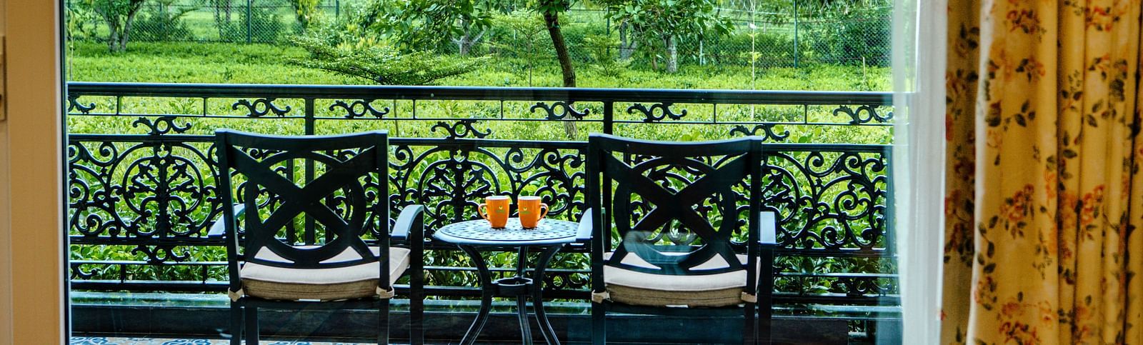 two chairs and a table kept in the balcony of a room - Mayfair Tea Resort, Siliguri