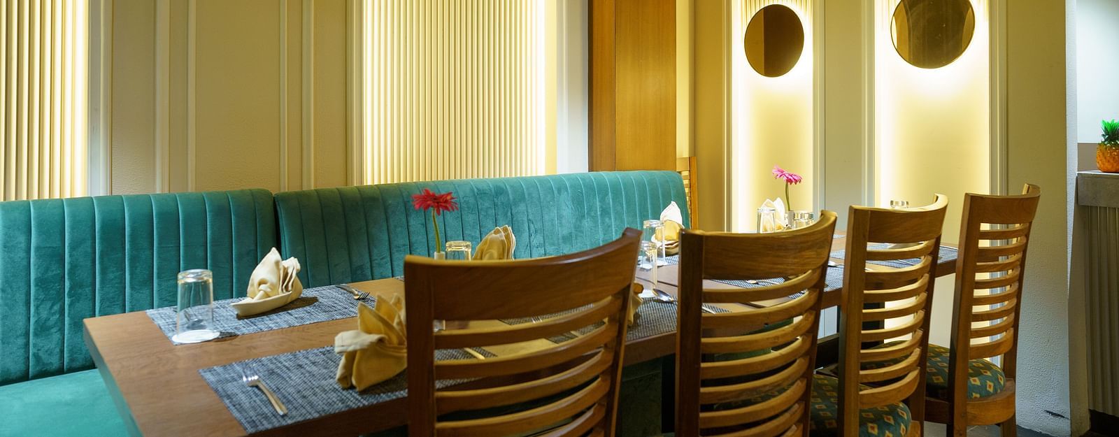 A wide shot of a dining area with booths featuring turquoise upholstery and wooden tables at Orsino Spa Resort.