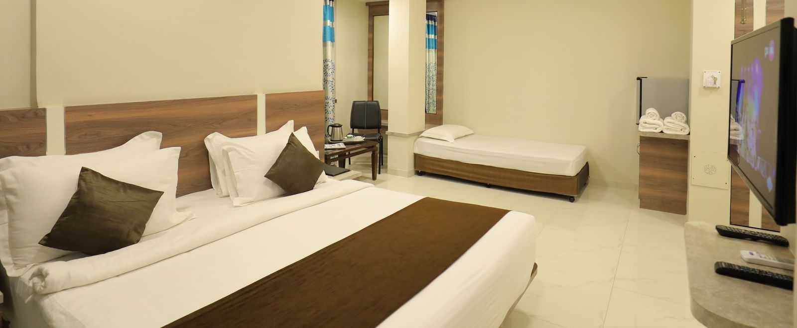 Close up of the king size bed and single bed in the Suite of Highland Resort, facing a wall-mounted TV.
