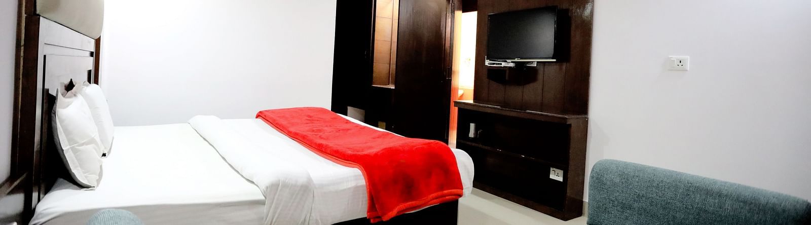 Side view of a room with a bed and a sofa on the side with a coffee table in front of it at Amara Hill Queen, Mussoorie.