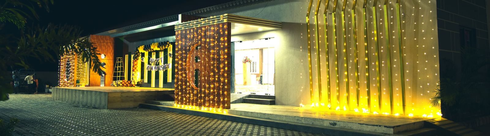 Night view of Daksh Hotels and Resorts with illuminated entrance and modern architecture.