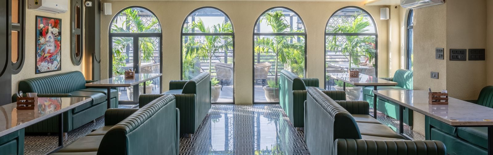 Huge dining space with arched windows, green sofas, and glossy flooring at Hotel Highway King, Jaipur.