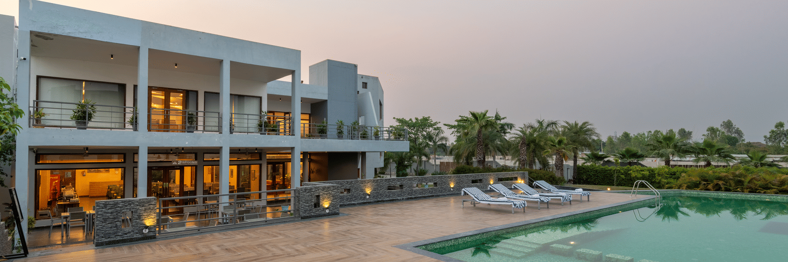 Facade view of DLS Forest Vines Resort on one side and the pool on the other, set against the sky.