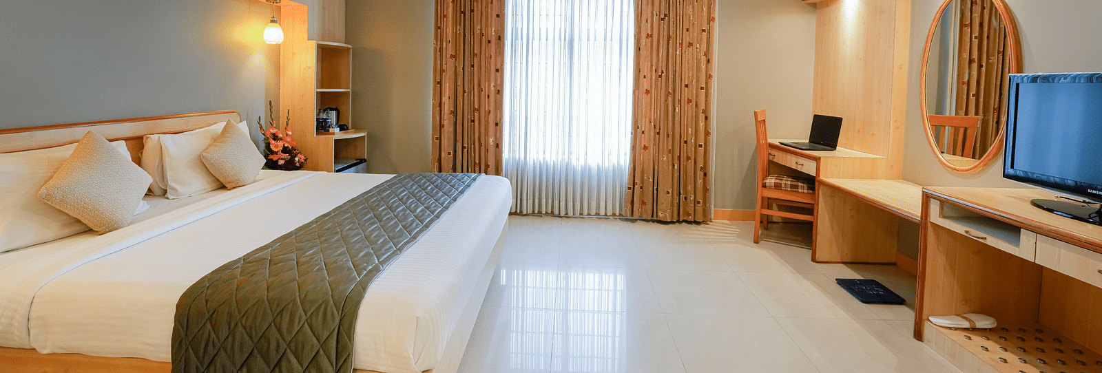An image of a Suite with plush bedding, a work desk, and ample natural light - Cross Roads Inn, Bengaluru