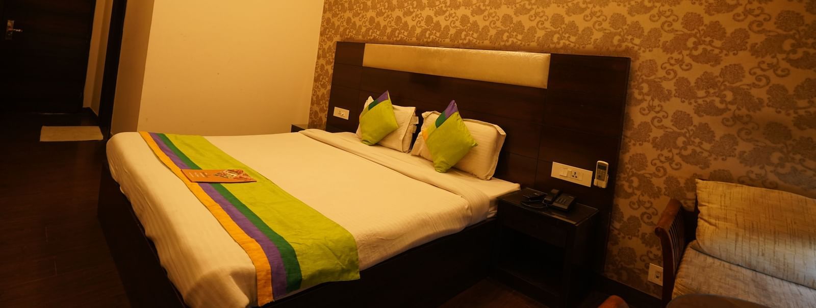 King-size bed with bedside table, AC and private bathroom in the Deluxe room at Hotel Dreamland, Chandigarh