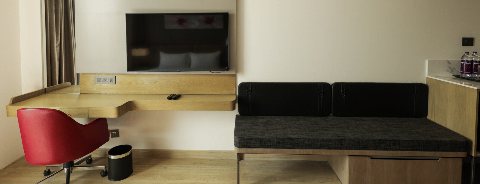 Contemporary room with red accent chair, black sofa, and mounted flat-screen TV at Ramada by Wyndham Sonipat Murthal