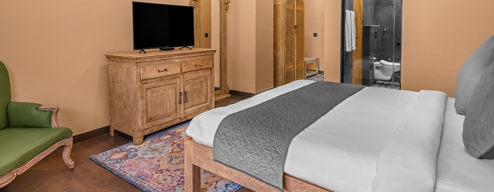 a bedroom with a large bed facing a television - Atman, Dharamshala