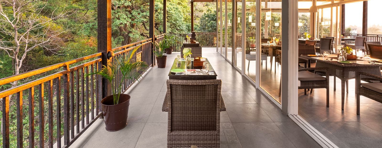 Balcony dining scene overlooking lush forest, with table set and chairs at Bedzzz, Rishikesh