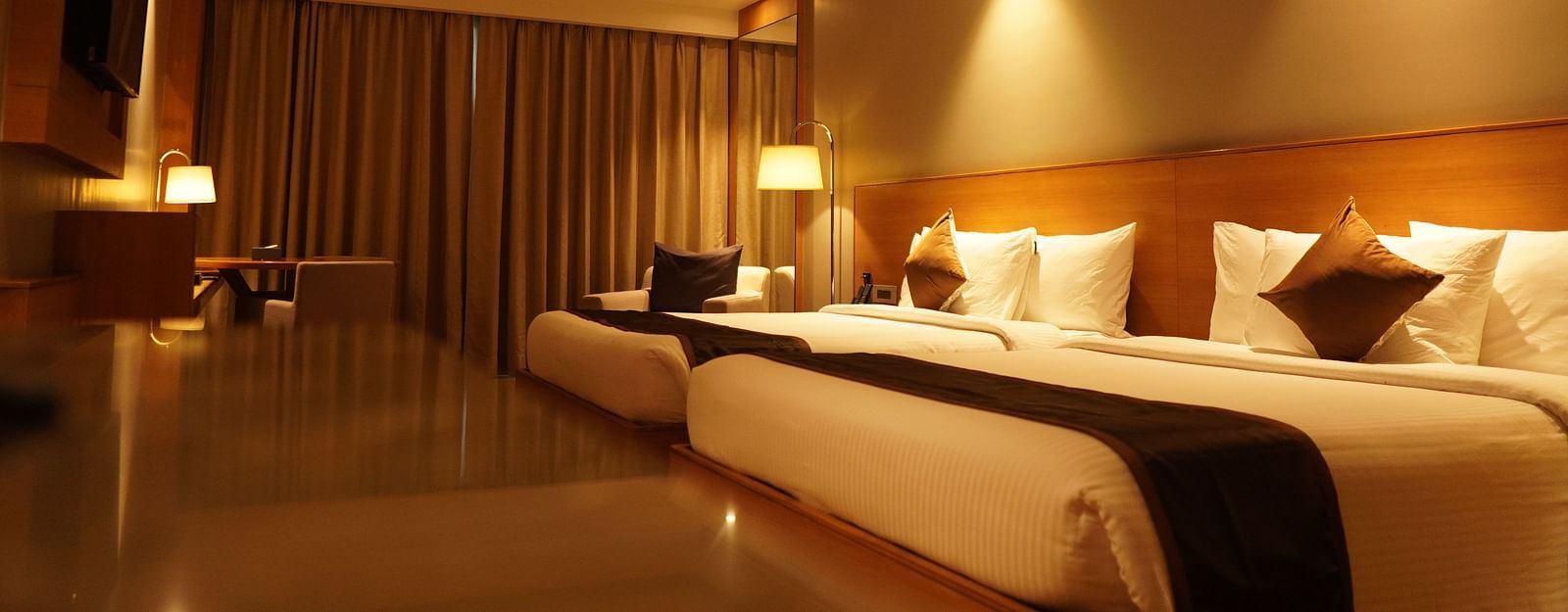 Two spacious beds with warm lighting and neatly made sheets