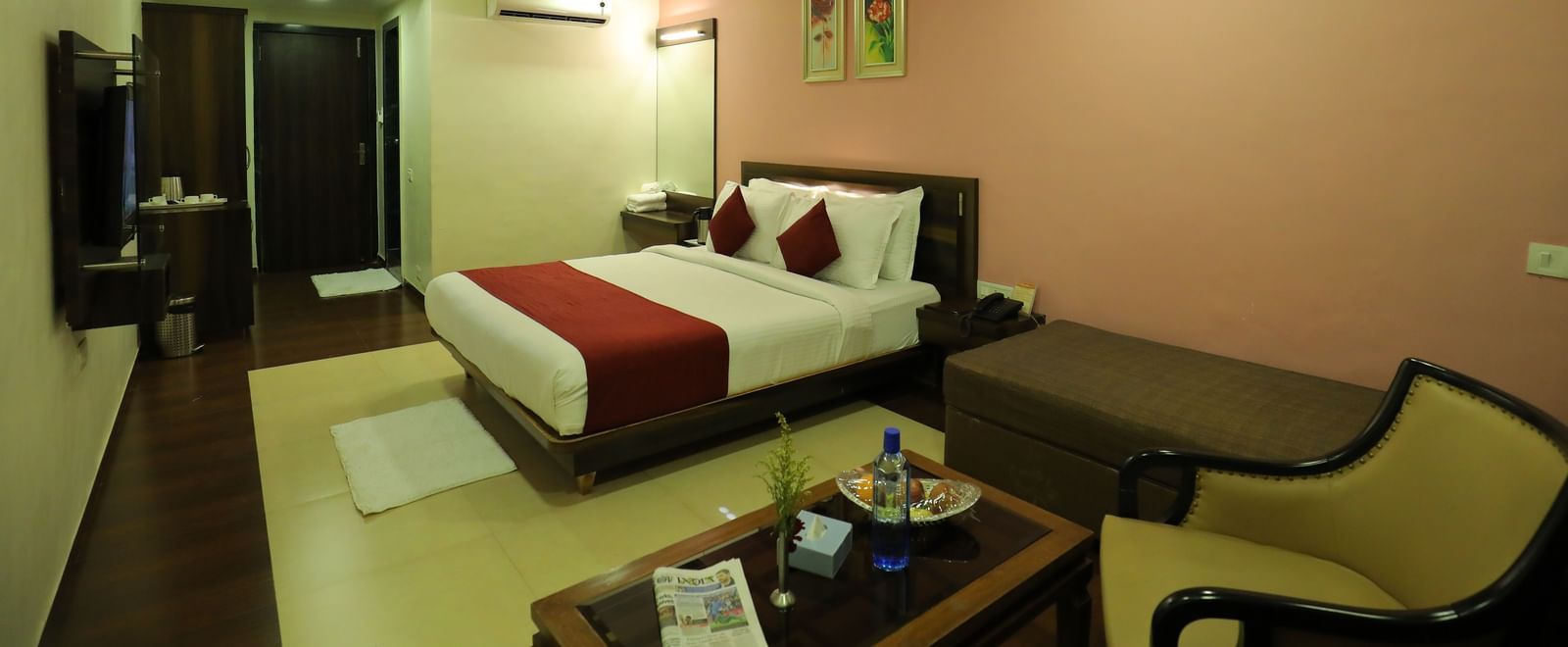 A spacious bedroom at Krushnai Resort with lounge chairs, coffee table, and a well made double bed.