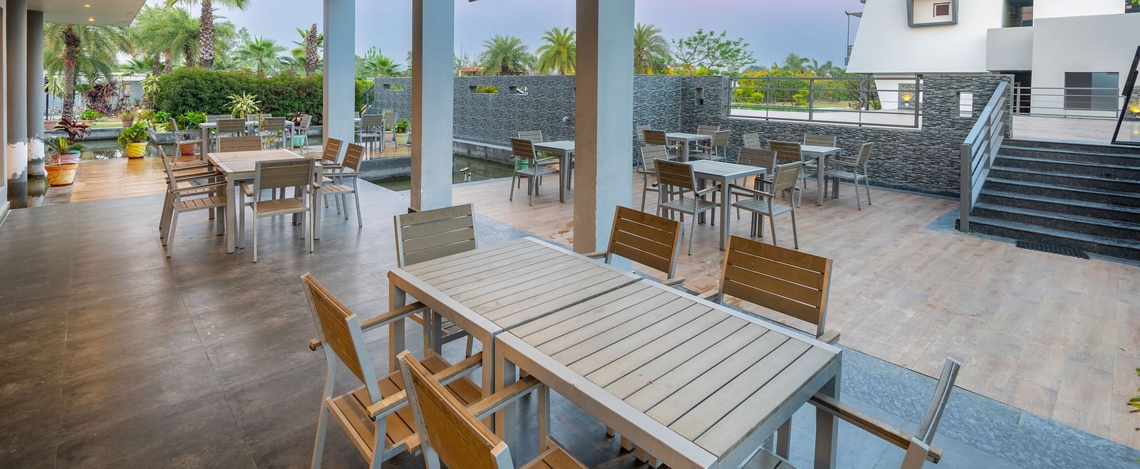 Outdoor dining area at DLS Forest Vines Resort with wooden tables and chairs.