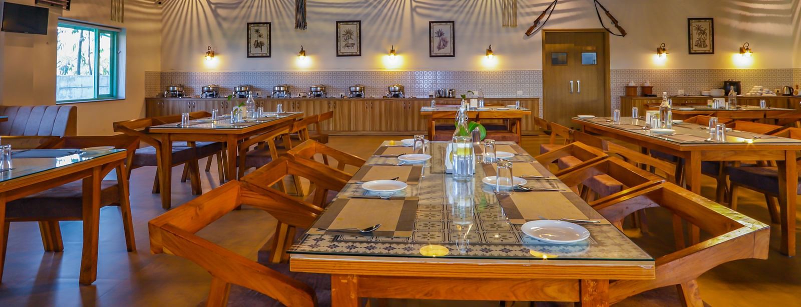 A long table with chairs extends through a well-lit dining area at Vedikant Resorts The Mallard Corbett.