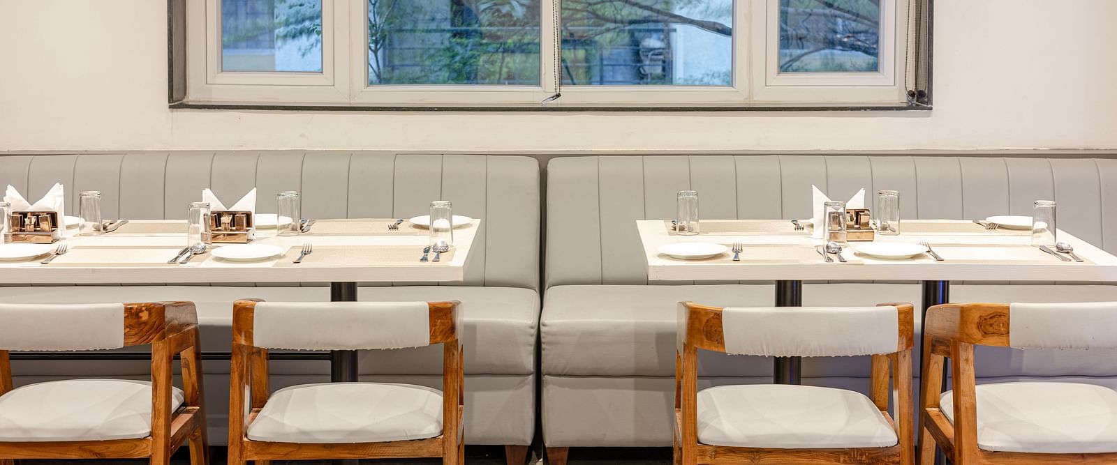 Window-side dining tables in the in-house restaurant at Lemonridge Hotels, IDPL Balanagar