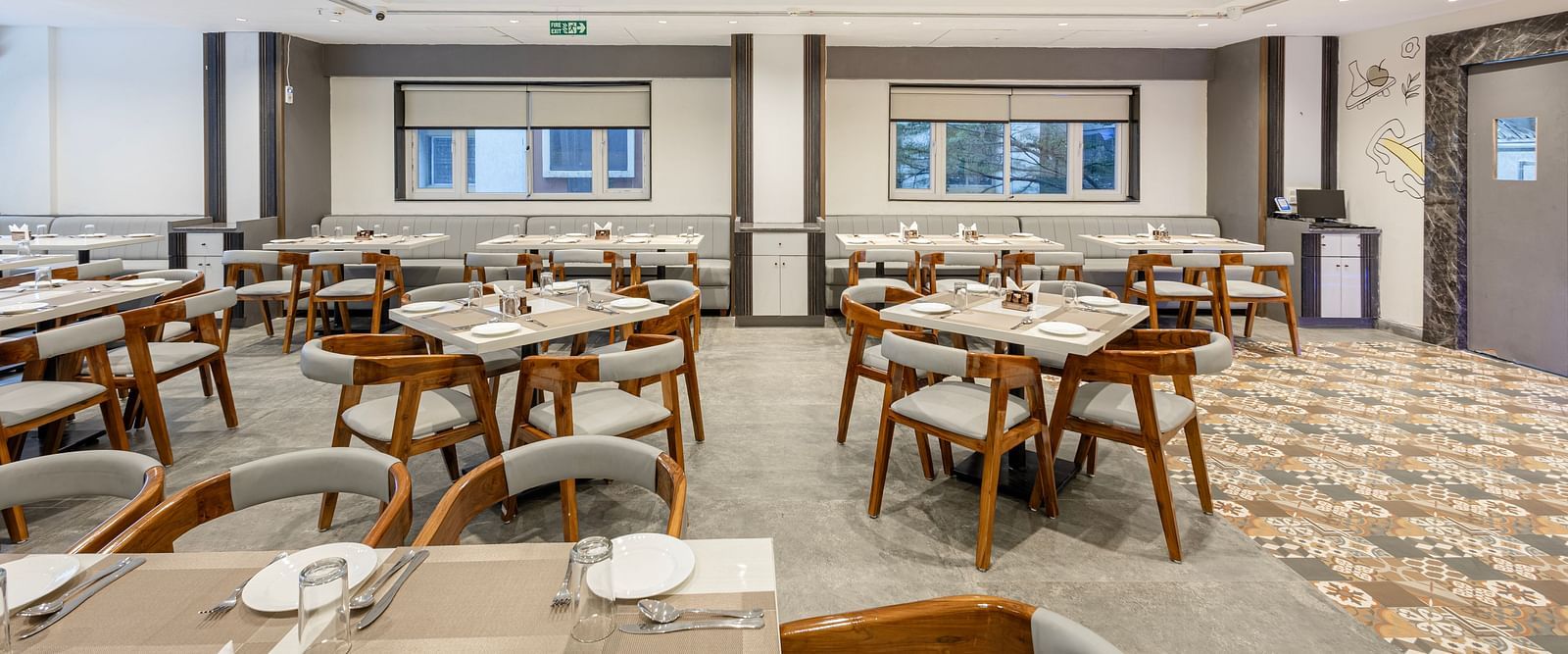 Modern restaurant dining setup with wooden chairs and white tabletops at Lemonridge Hotels, IDPL Balanagar.