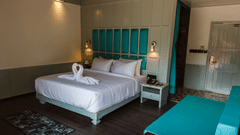 A double bed with dove towels, side stand, and lamps inside the Hill Villa at Symphony Samudra Beachside Jungle Resort And Spa, offering one of the finest Port Blair Villas.