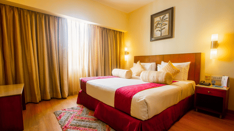 Executive Suite with a king size bed, red bedspread and warm ambient lighting at Featherlite Evoma Hotel.
