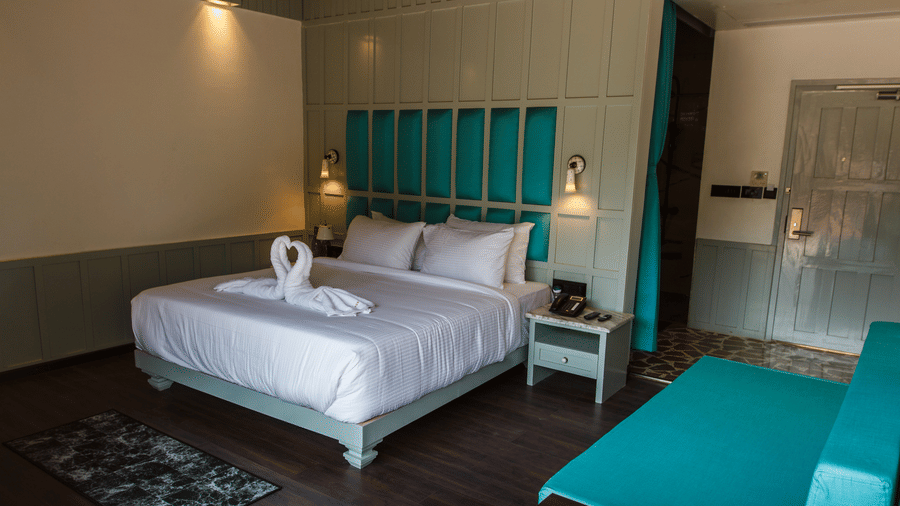 A double bed with dove towels, side stand, and lamps inside the hill villa room at Symphony Samudra Beachside Jungle Resort And Spa | Port Blair Villas
