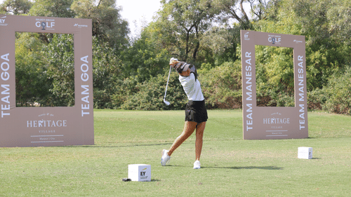 Professional golfer taking a swing at a golf course during a branded tournament event.