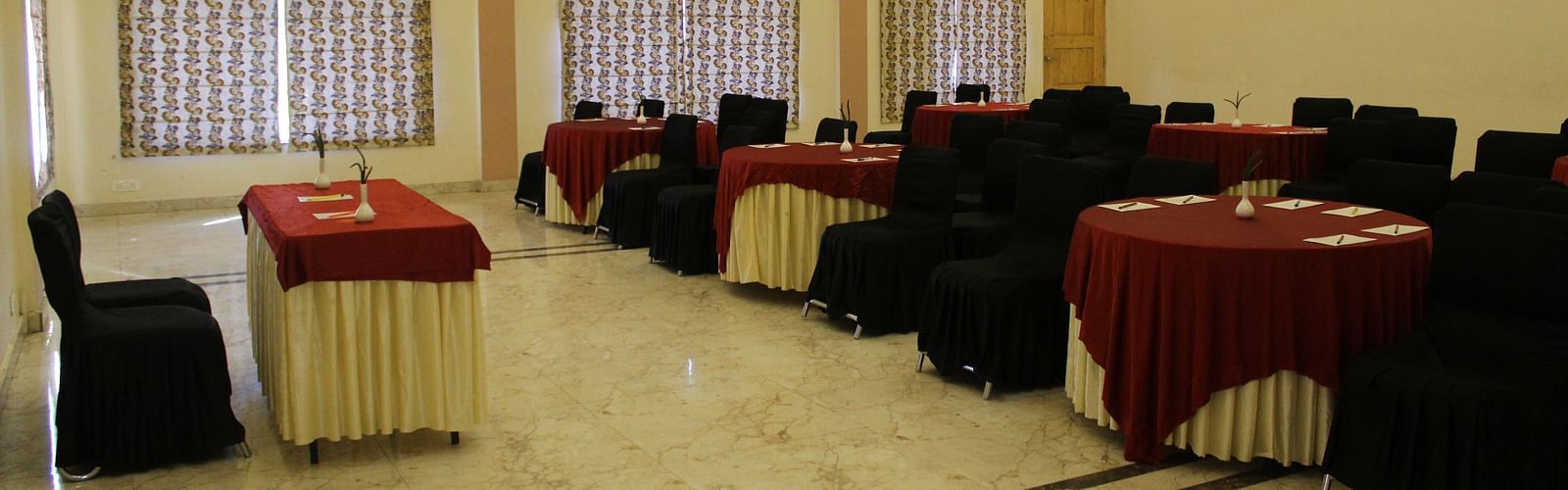 Side angle of the banquet hall, showcasing bright lighting, well-arranged tables, and a polished floor at Dagshai Manor Kasauli - Inde Hotels.