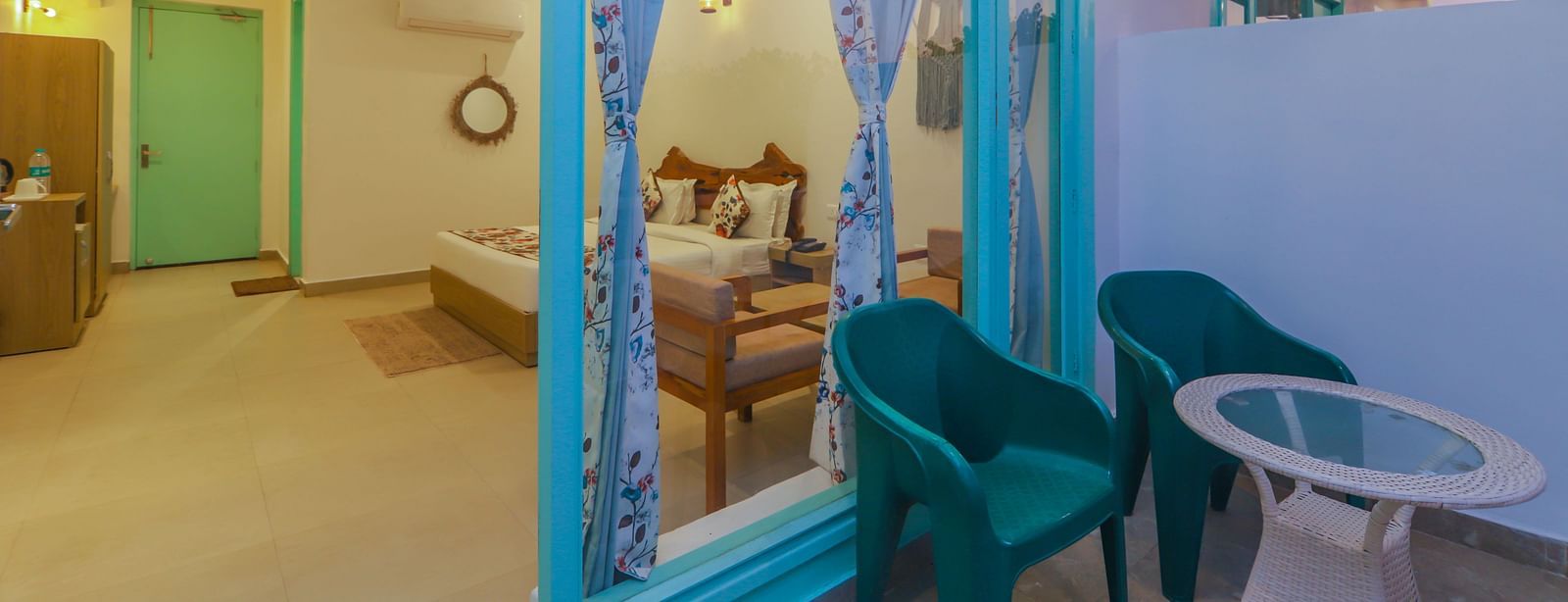 A bright room at Vedikant Resorts The Mallard Corbett opens to a balcony with chairs and a table.