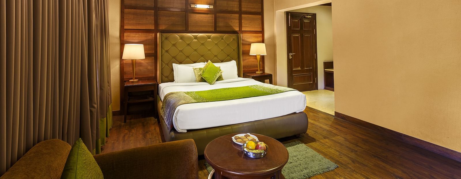 a bedroom with a large bed and side lamps, a table and a sofa - The Earl's Court, Nainital