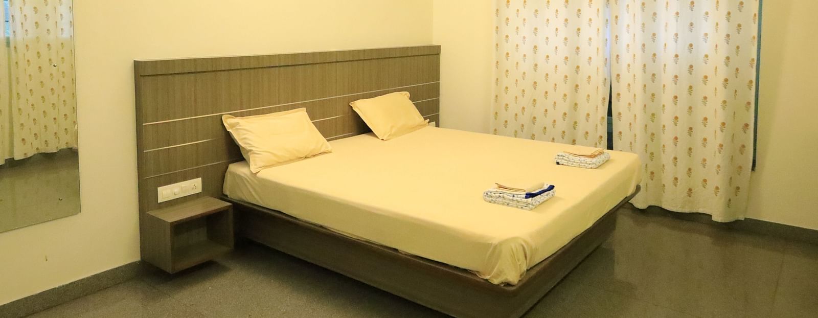 A well-lit bedroom with a comfortable bed with a head board and curtains.