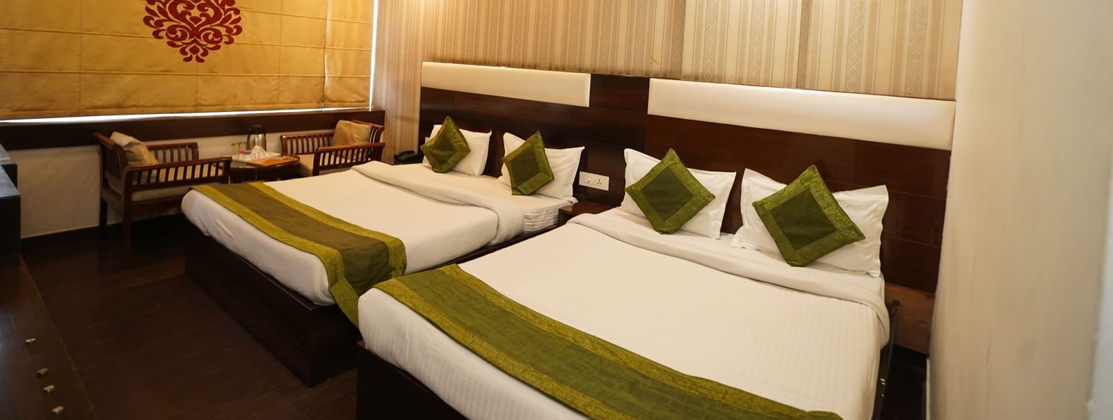 Spacious Family room at Hotel Dreamland, Chandigarh with King-size bed, two seating chairs with centre table, ceiling fan, AC with curtain rolled down.
