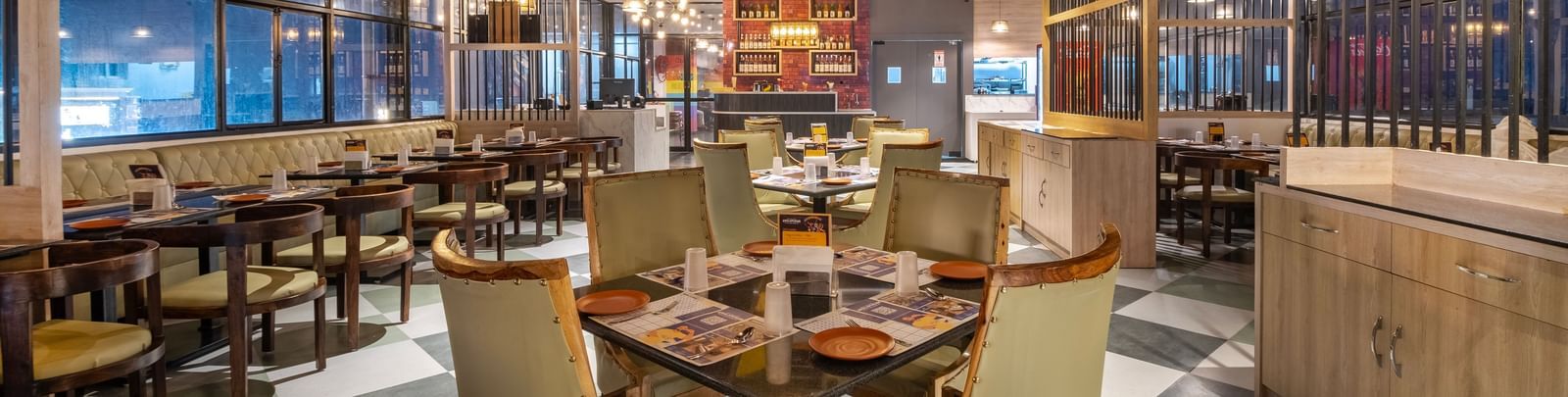 Dining space at Monday Hotels Amalapuram Heights with elegant seating, colourful seating, and city views.