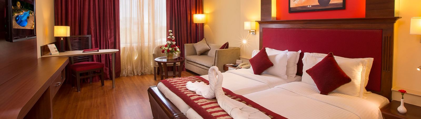 Superior Room featuring twin beds, sofa and a television at Hotel Atithi - TGI Grand, Pondicherry