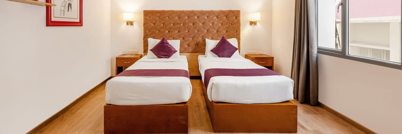 A hotel room with 2 single beds. a ceiling fan and a large window with the curtains opened - Monday Hotels HITEC City, Hyderabad
