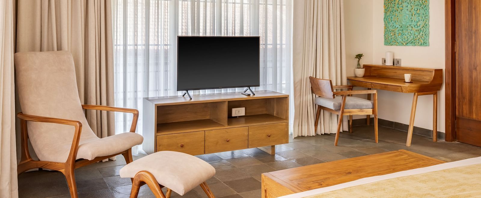 A modern bedroom with a comfortable bed, a television, and a seating area, complemented by large windows and soft curtains - BluSalzz Villas - Alocassia, Anjuna