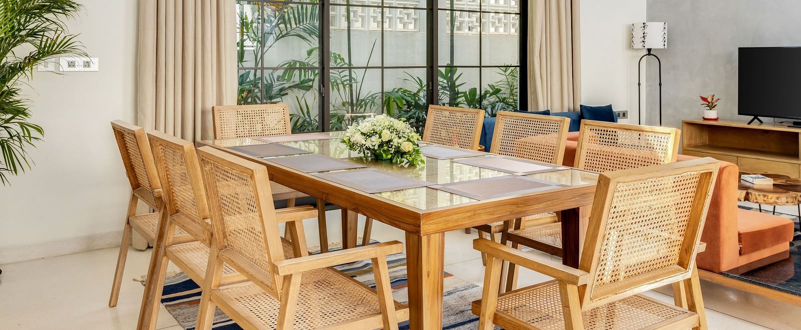 A dining area with a contemporary wooden table, modern chairs, and large windows bringing in natural light - BluSalzz Villas - Alocassia, Anjuna