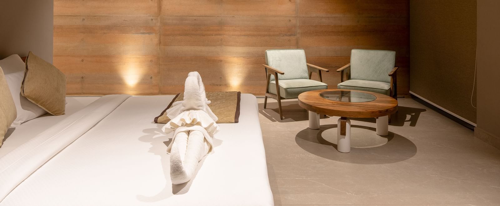 A spacious living area with textured wooden walls, a seating arrangement, and a rug on the floor | Gaia Room | RD's Nature Retreat, Bangalore