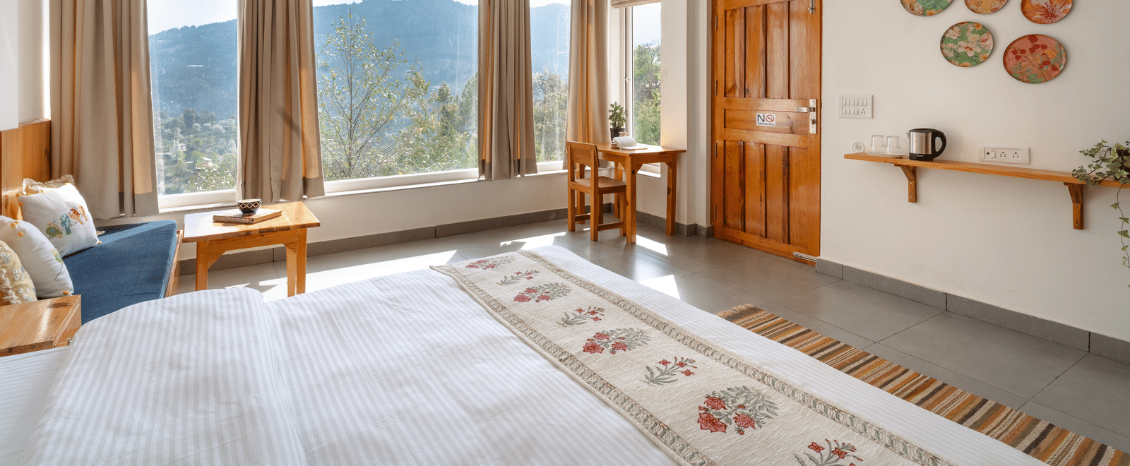 A bedroom at Ziran Retreat with a bed, a small sitting area, and large windows with a scenic view.