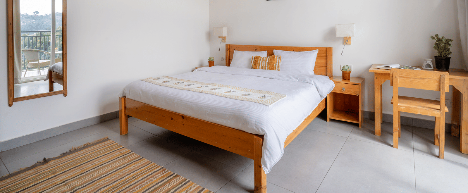 A bedroom at Ziran Retreat with a large bed, a wooden bedside table with a lamp, and a window with a mountain view.