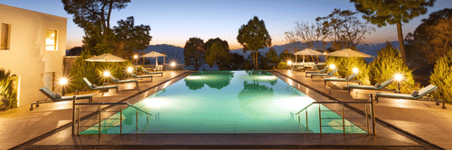Image of a large swimming pool at Suryavilas in the evening as the premises are surrounded by trees