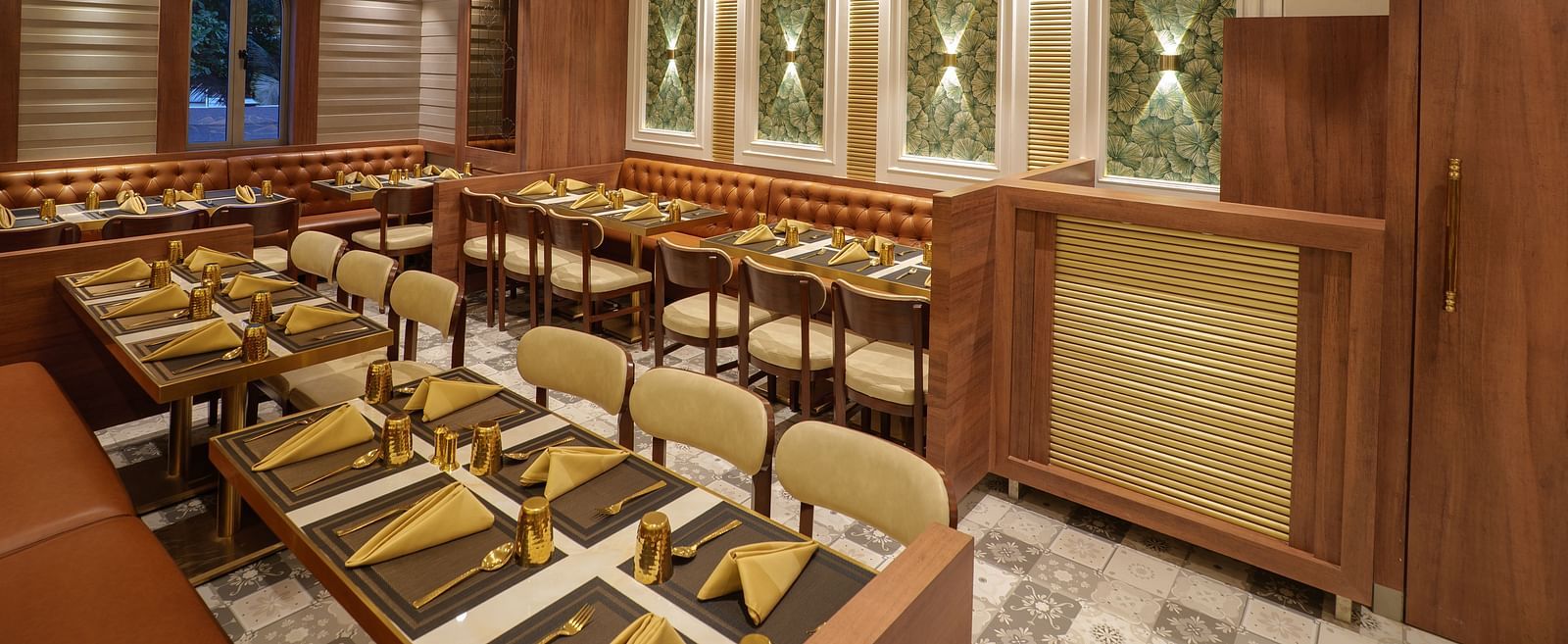 A well-lit restaurant displays set tables, wooden chairs, warm lighting, and decoration on the walls - Melior Inn