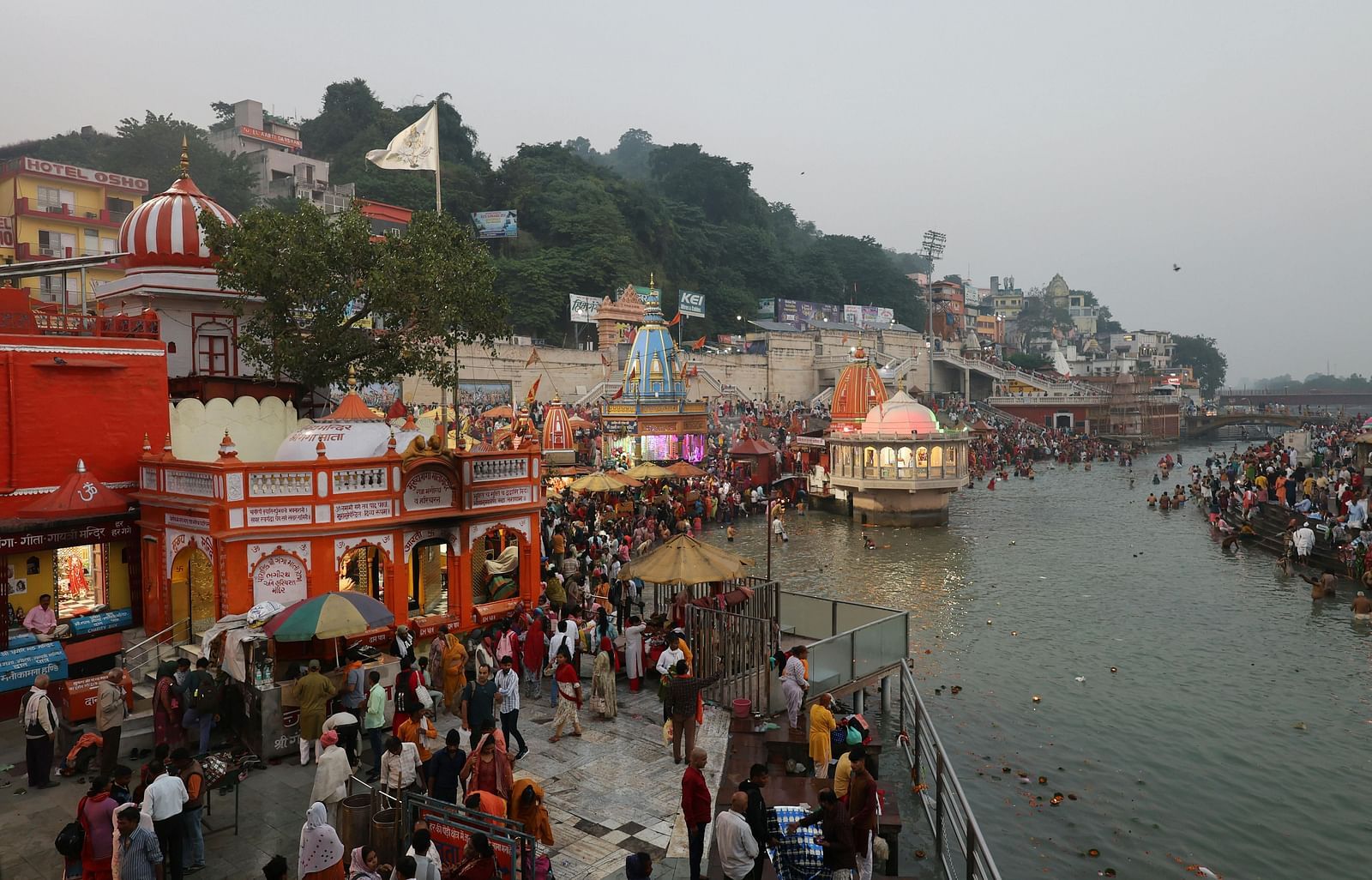 An image of few temples near Ganga river and there are many devotees outside the temples