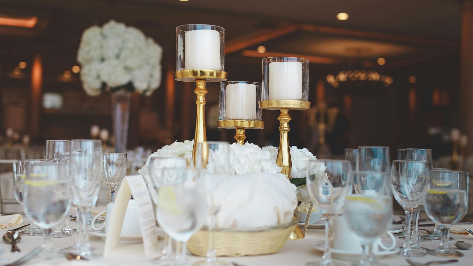 Sophisticated banquet table with gold candlesticks and white floral centrepieces