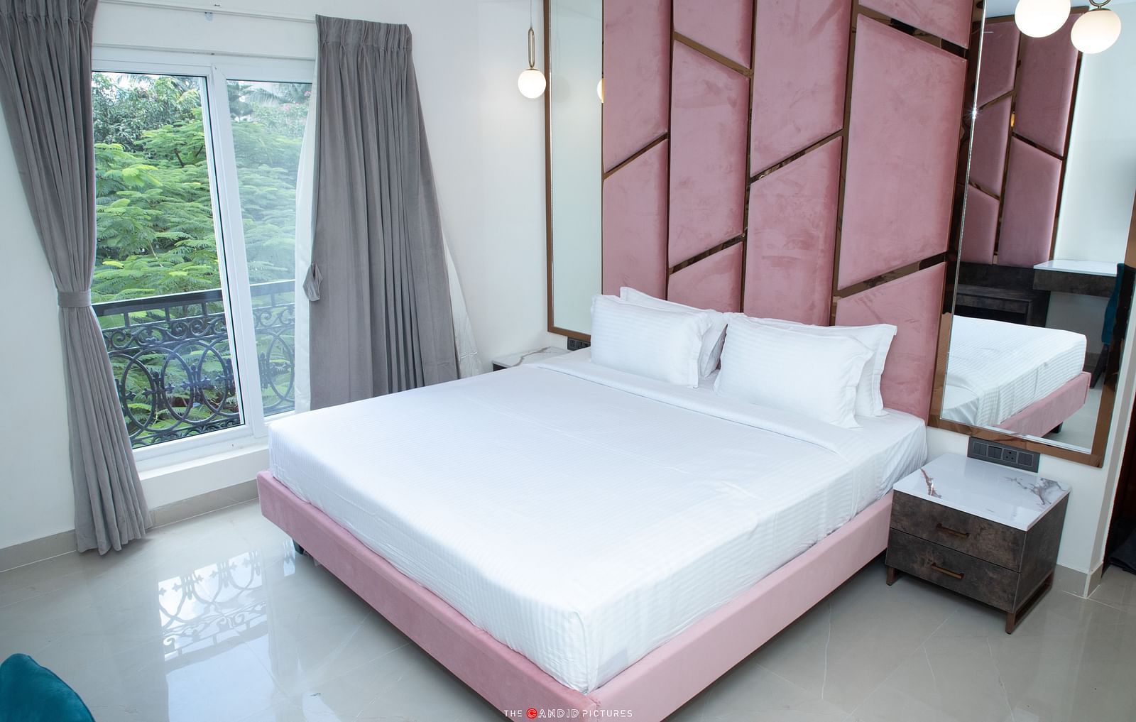 corner view image of the premium room with a double bed and a balcony besides it with lush green views - Astra Hotels and Suites, Koramangala