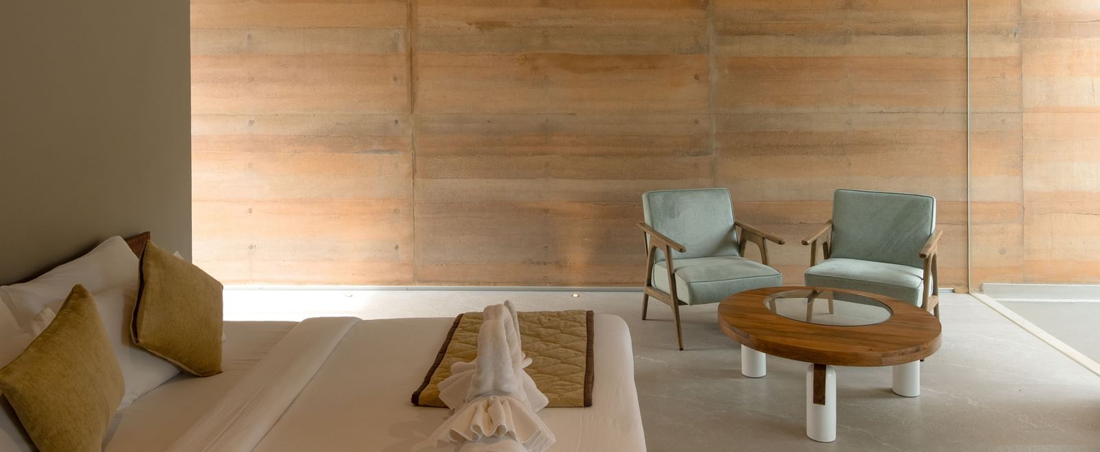 An interior living space with textured walls, minimalist furniture, and a central coffee table | Gaia Room | RD's Nature Retreat, Bangalore