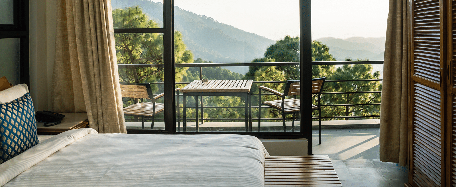 A bedroom with a balcony offering natural light and scenic views at BluSalzz Escapade Resort, Lansdowne