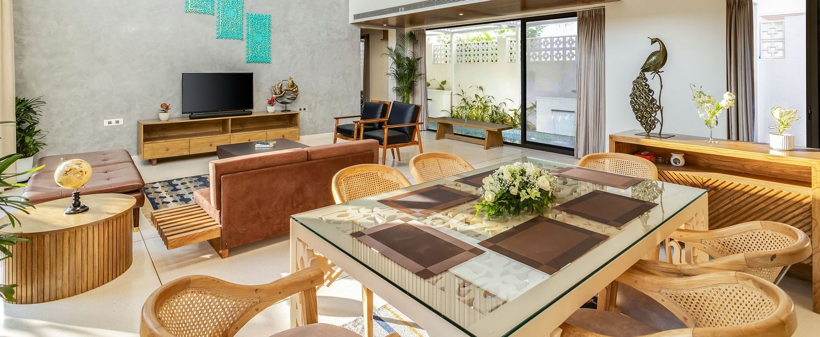 A bright and modern dining area with a large wooden table, contemporary chairs, and an open-plan kitchen in the background - BluSalzz Villas - Alocassia, Anjuna