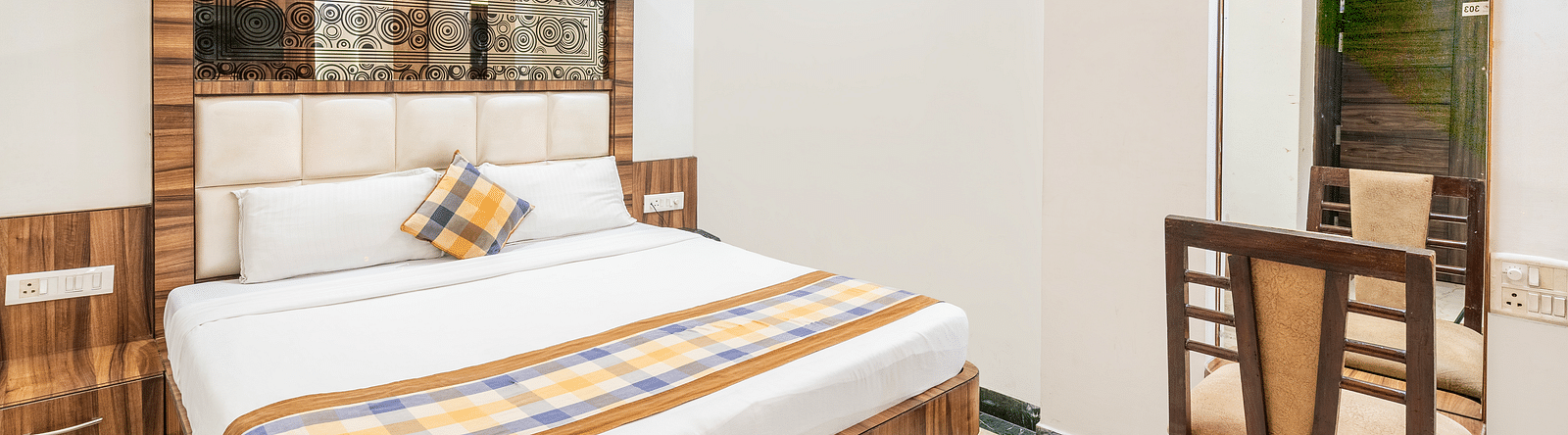 A side angle view of the bedroom at Hotel Moti Palace, featuring a comfy bed and a dressing table.