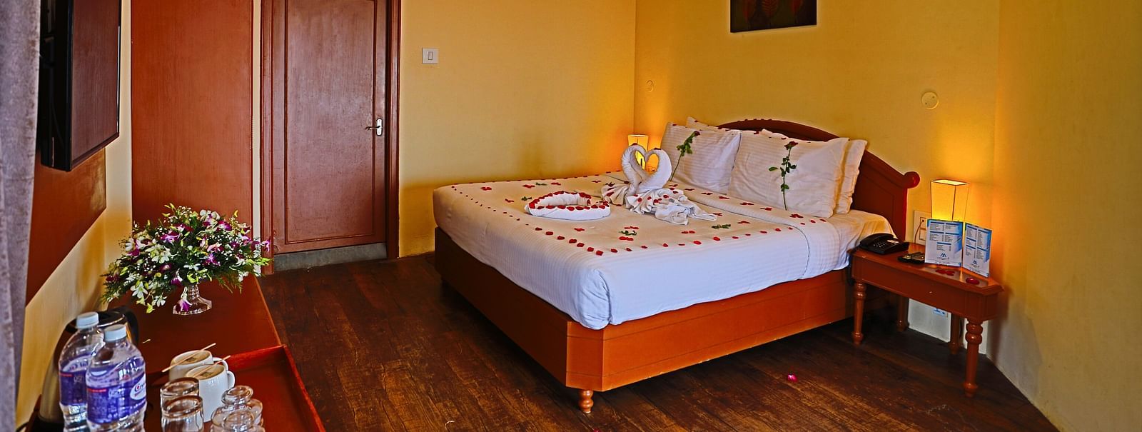 a plush white bed decked with flower petals at La Montana By TGI, Ooty