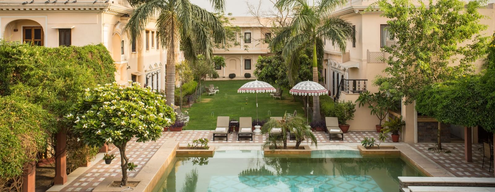 An outdoor scene features a swimming pool in front of Royal Heritage Haveli with palm trees.