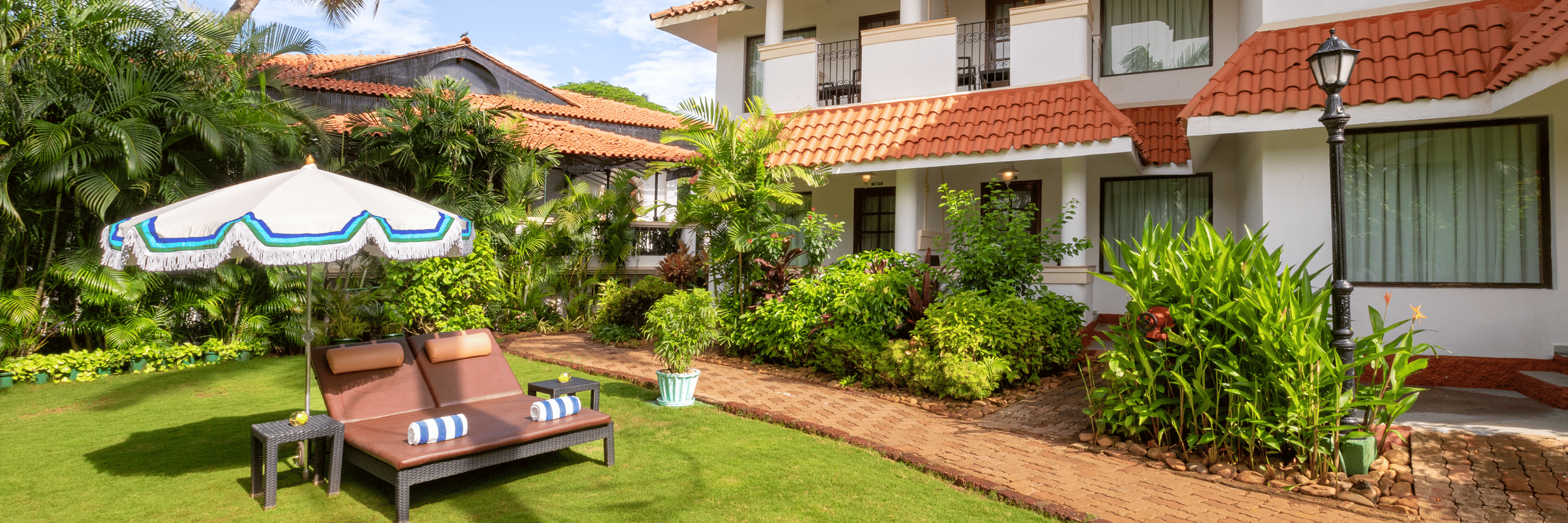 Heritage Village Resorts & Spa, Goa features lush gardens, sun loungers, and charming Portuguese-style architecture.