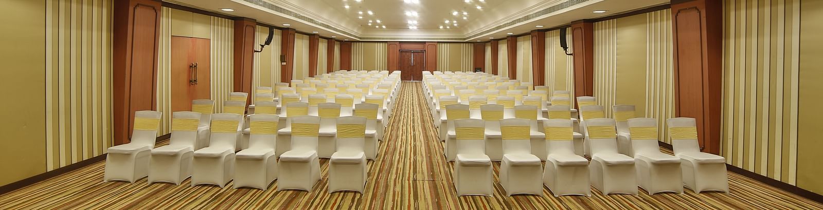  Seating arrangement in Terrace Hall A grand hotel suite with an opulent red and white decor, large bed, and seating area, reflecting a traditional style at Sitara Luxury Hotel in Hyderabad near Ramoji Film City.