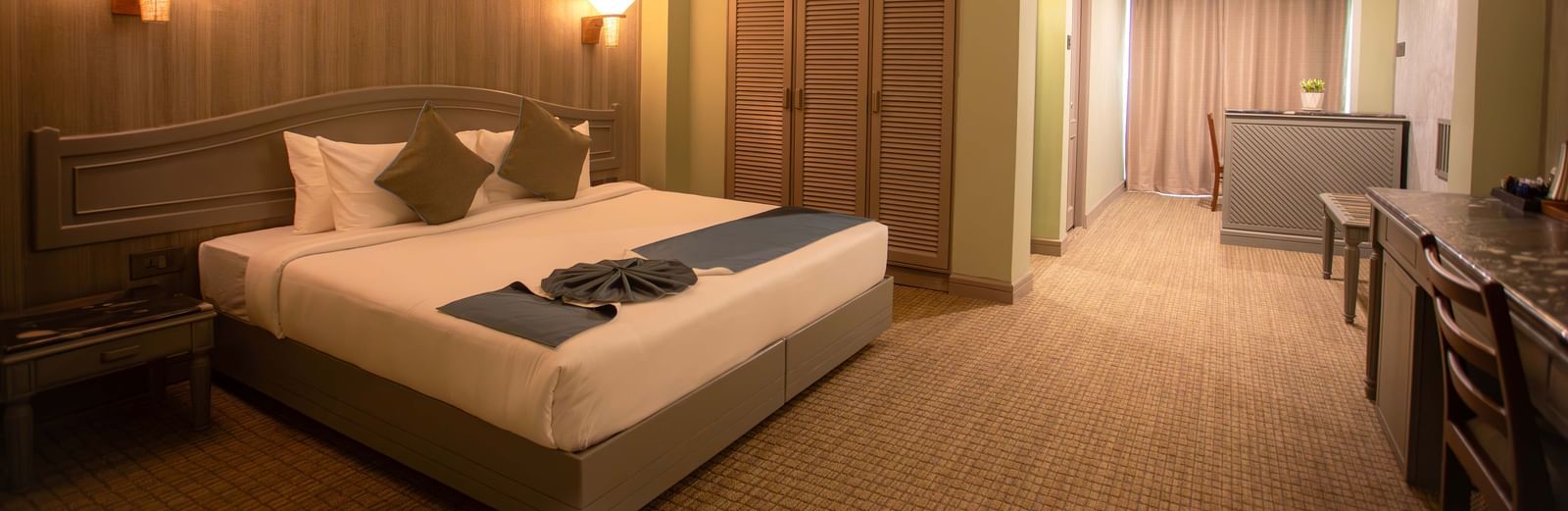  A spacious guest room at Shilton International, Kochi, with a bed, a desk area, and an adjoining room.